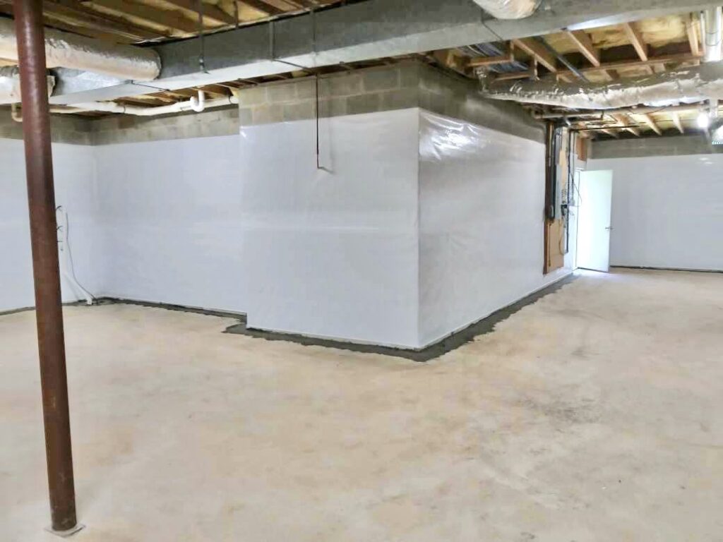 Finished basement waterproofing with sealed white wall liner and a dry floor
