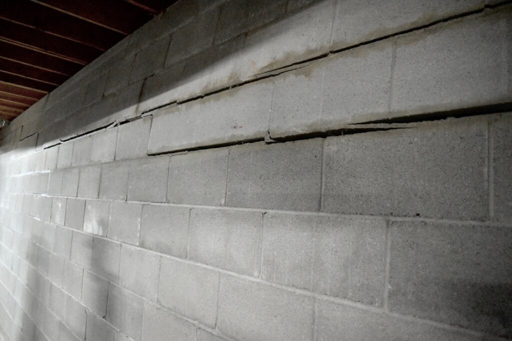 Block basement wall with a long horizontal crack and an inward bow, before repair
