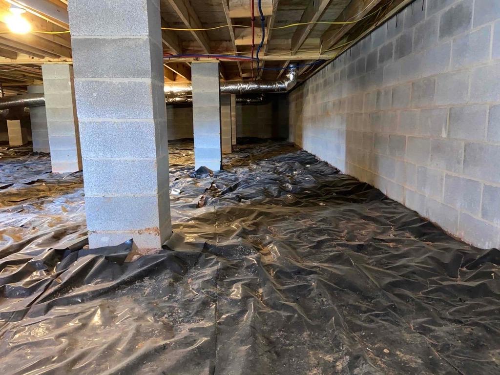 Crawl space in Piedmont, AL before encapsulation, with loose black plastic and bare block walls