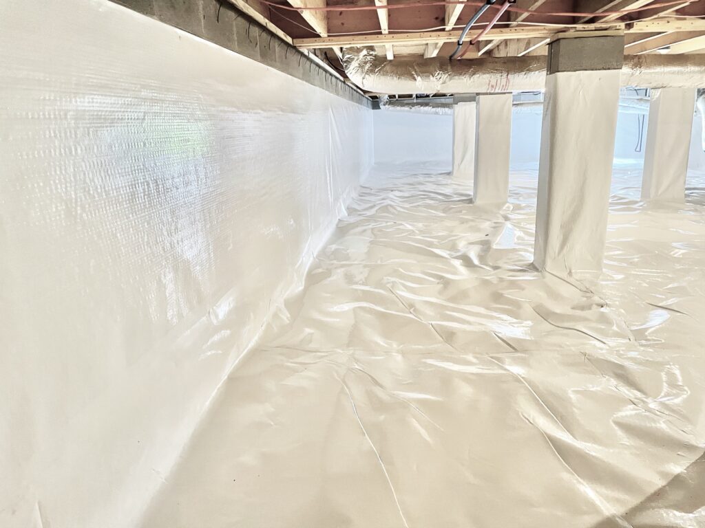 Encapsulated crawl space in Piedmont, AL with sealed white liner on the walls and wrapped piers